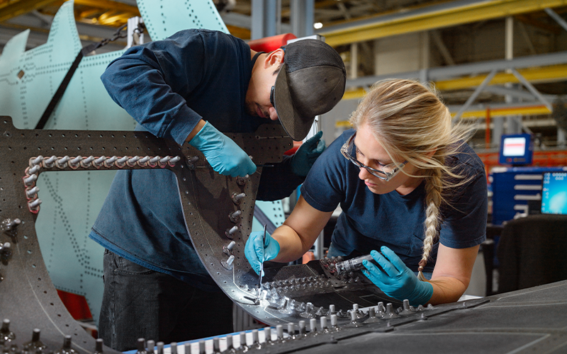 two people working on a part together