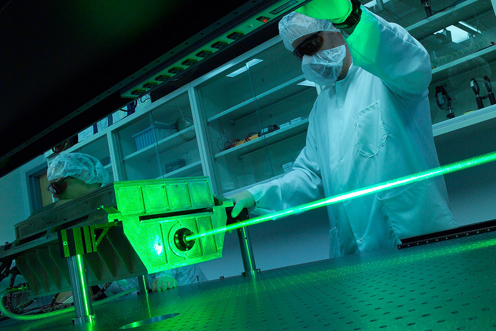 Man wearing protective eyewear and clean suit working on green laser
