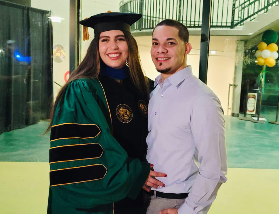 women wearing collage graduation robe standing next to man
