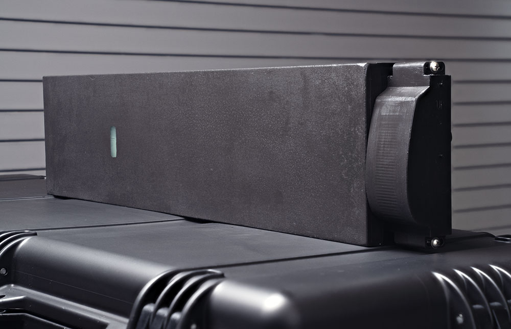 Black rectangular lithium-ion battery pack on a hard case, used for electric scooter charging.