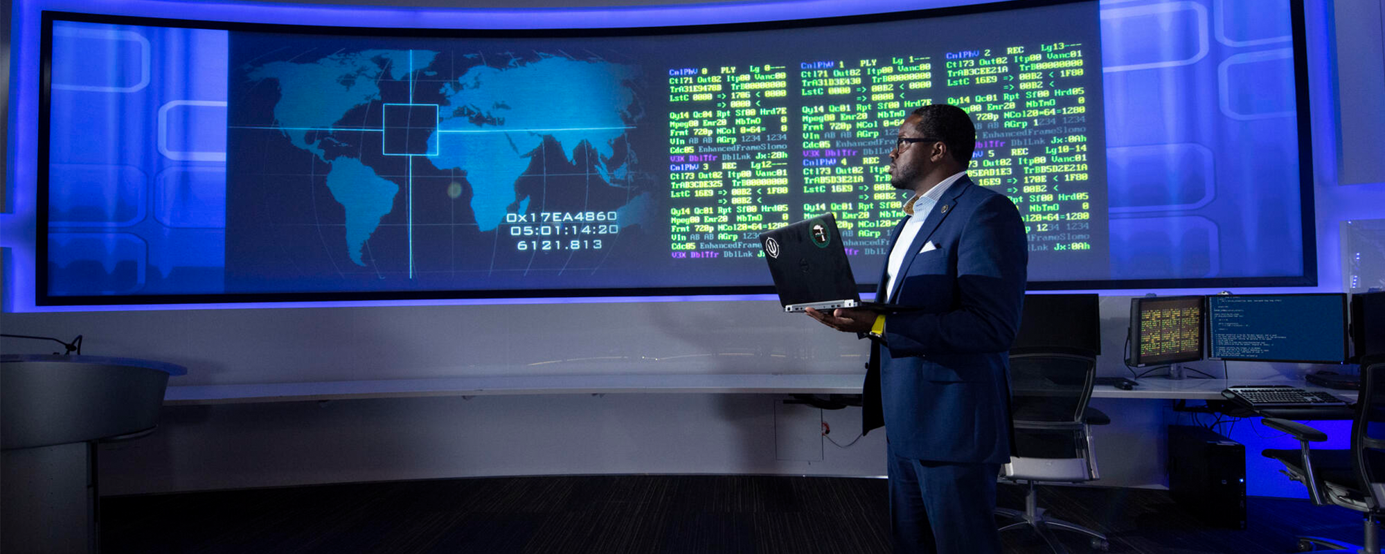 man holding a laptop looking at large screen