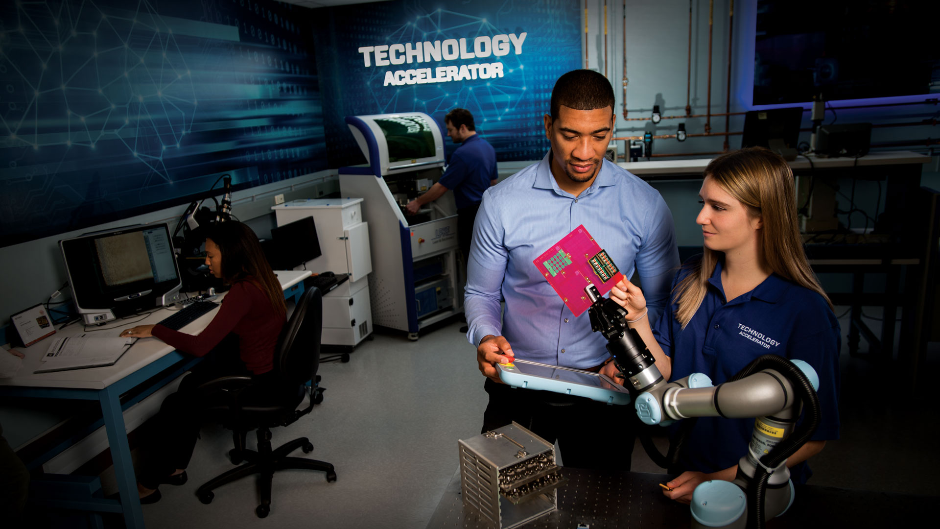 Professional man and woman looking at robot arm technology in technology lab.
