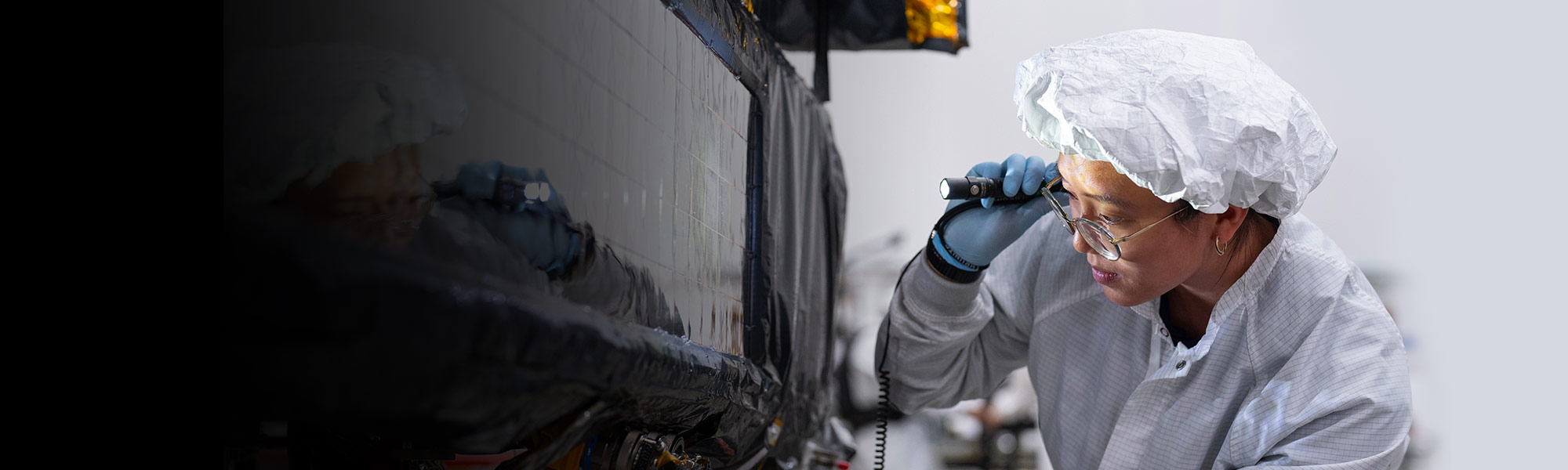 Female engineer in clean suit working on spacecraft