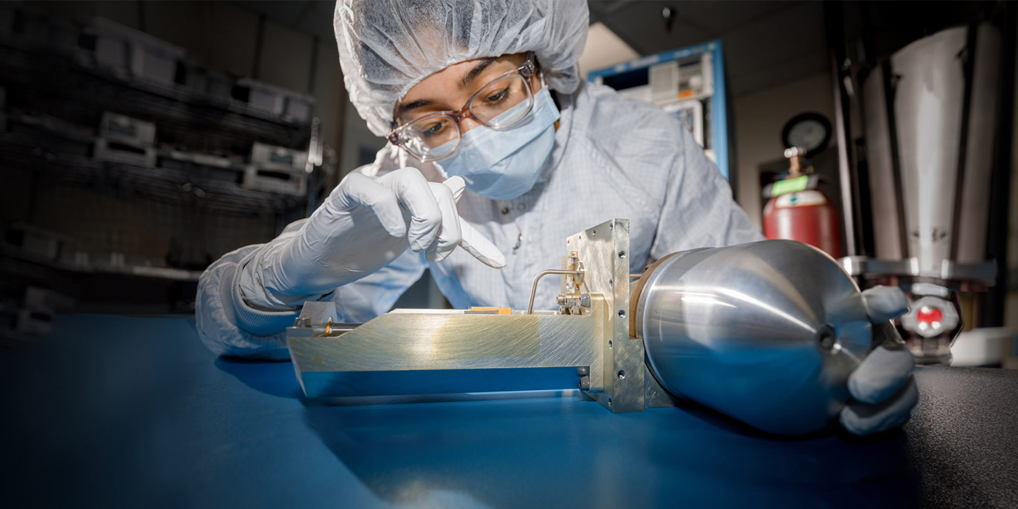 Female in lab suit next to cryocooler