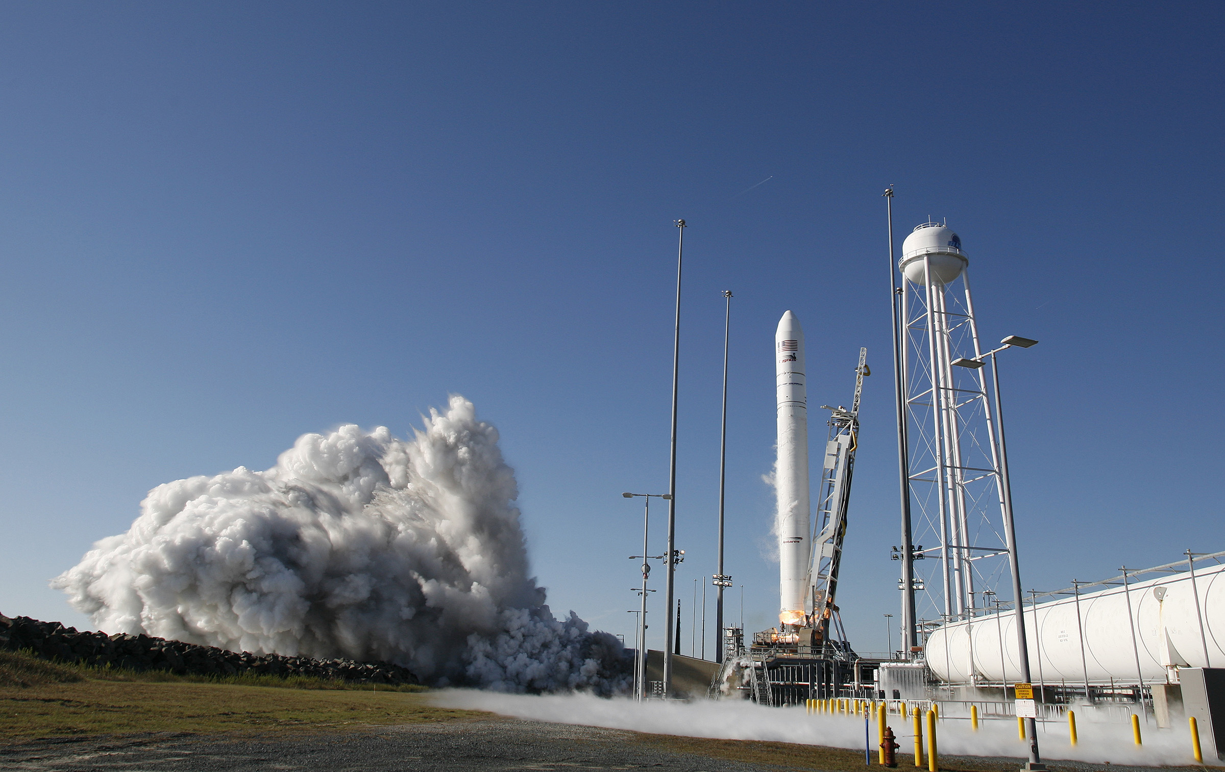 NG-12-Antares-Launch A rocket beginning to liftoff from launch pad in front of a blue sky
