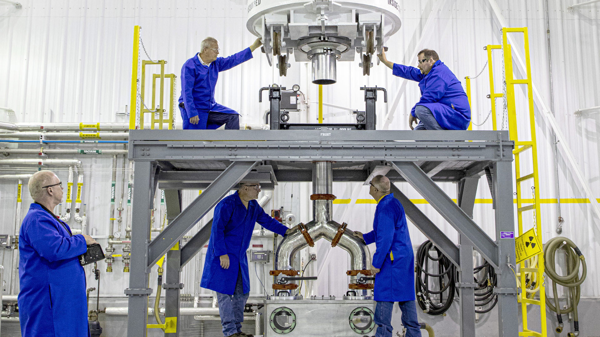 five workers with blue jumpsuits in propulsion facility
