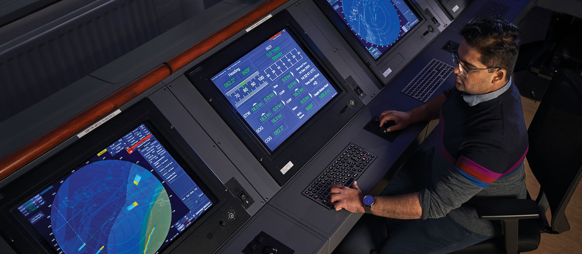 Image of man in darkened room viewing several technology monitors.