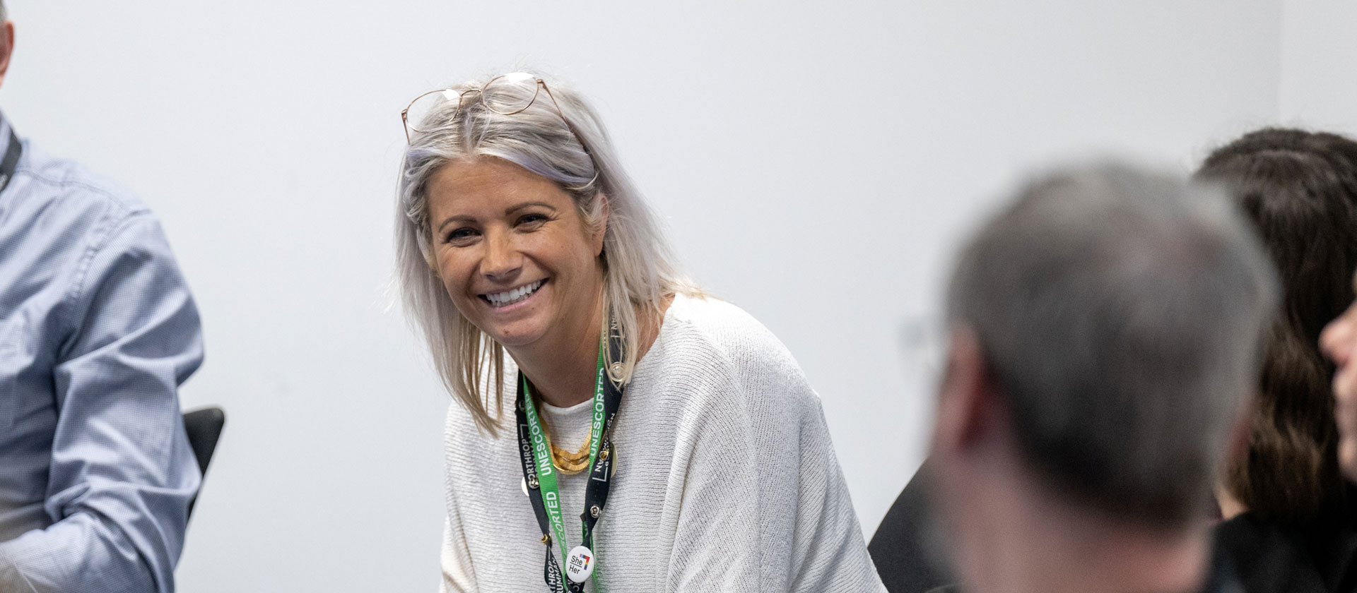 Image of a woman in group office setting smiling at coworkers.