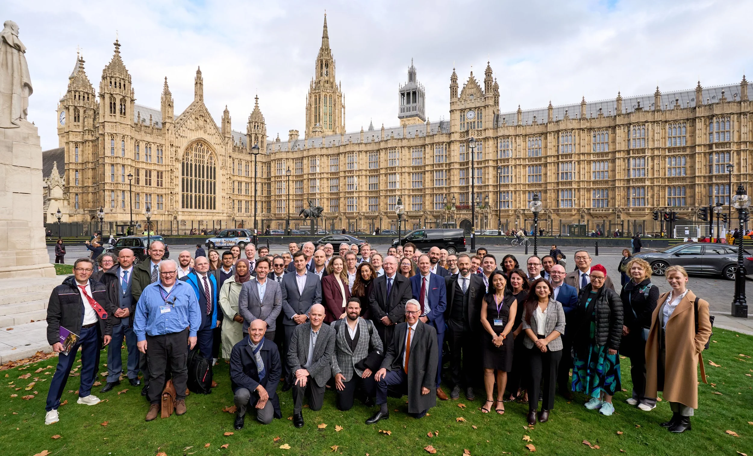 Photo of large group of people outside on college lawn in front of gothic buildings