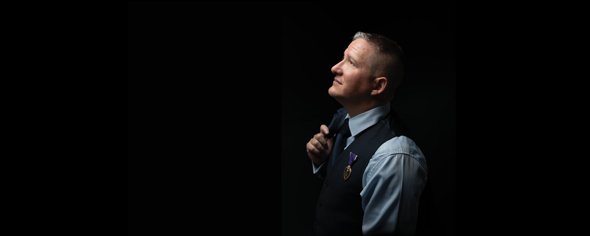 Veteran employee with coat over shoulder and black background.