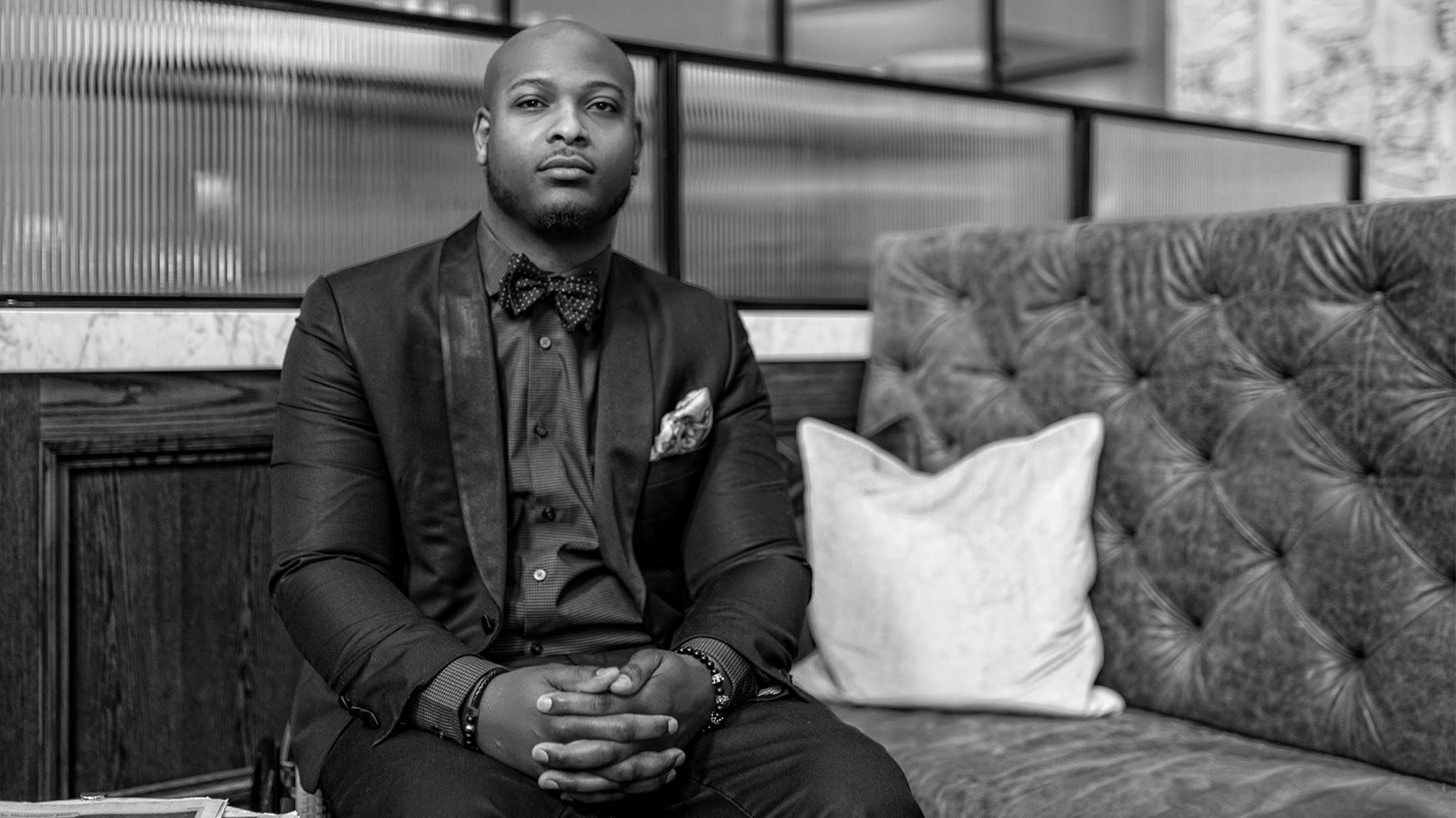 From Football Dreams to Higher Callings Black man wearing suit sitting on couch