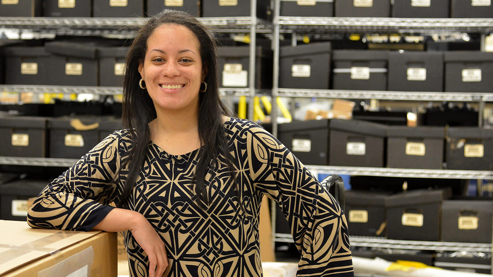 Global Supply Chain Management Star Featured in 30 Under 30 smiling black woman standing in front of shelves