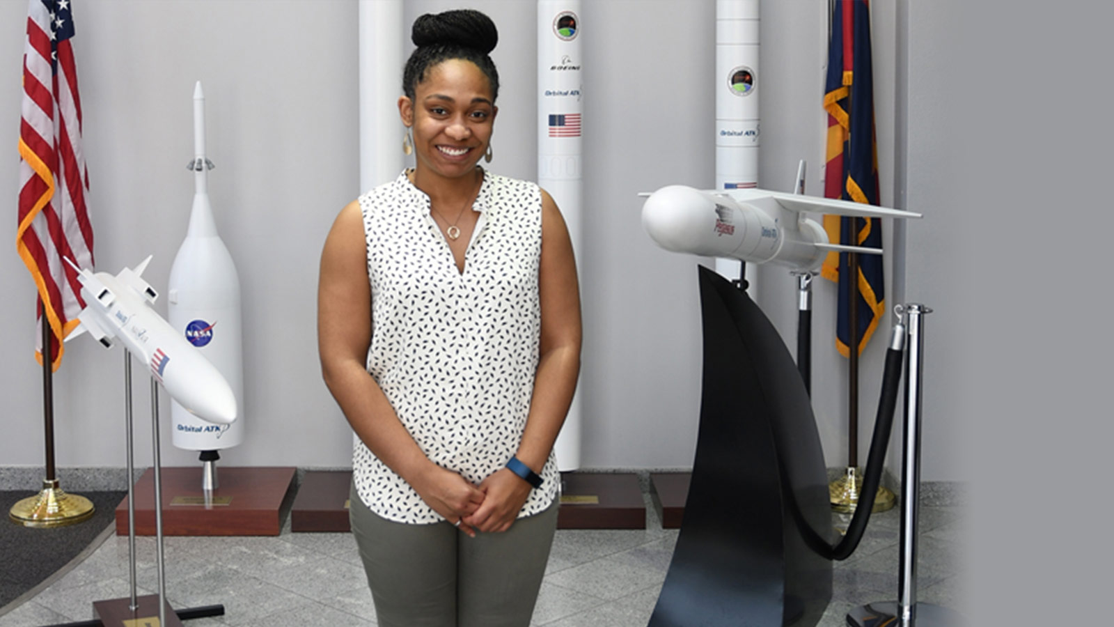 Growing With Technology: Mechanical Engineer Adds Value to Business Development Team black woman in front of rocket models