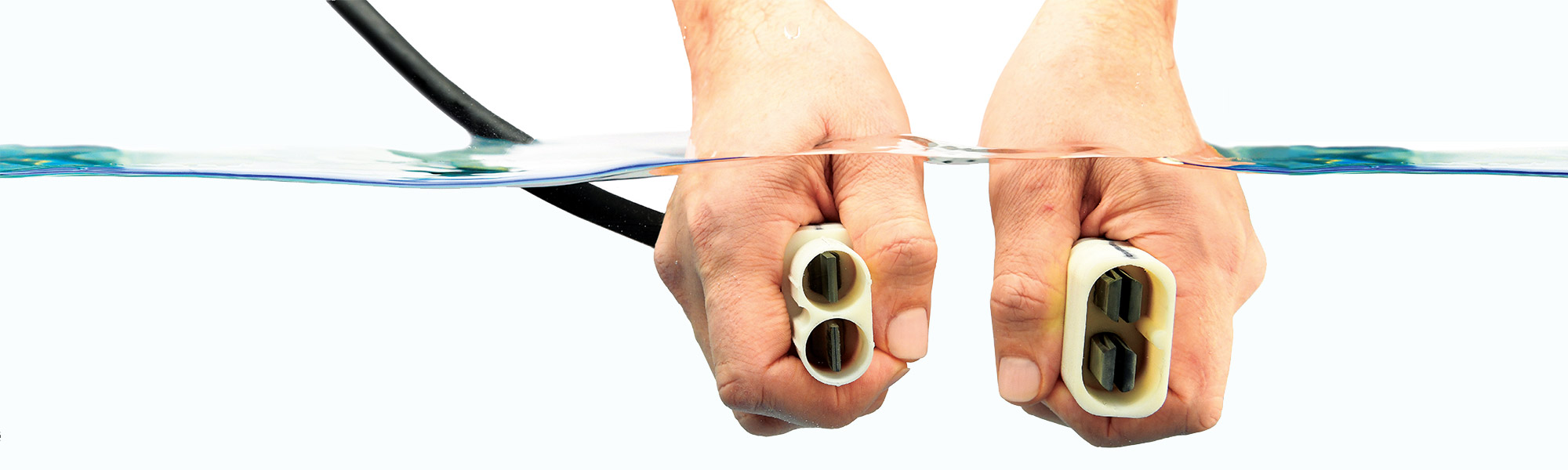 An Electricity and Water Pairing Pair of hands holding electrical cords, unplugged, underwater.