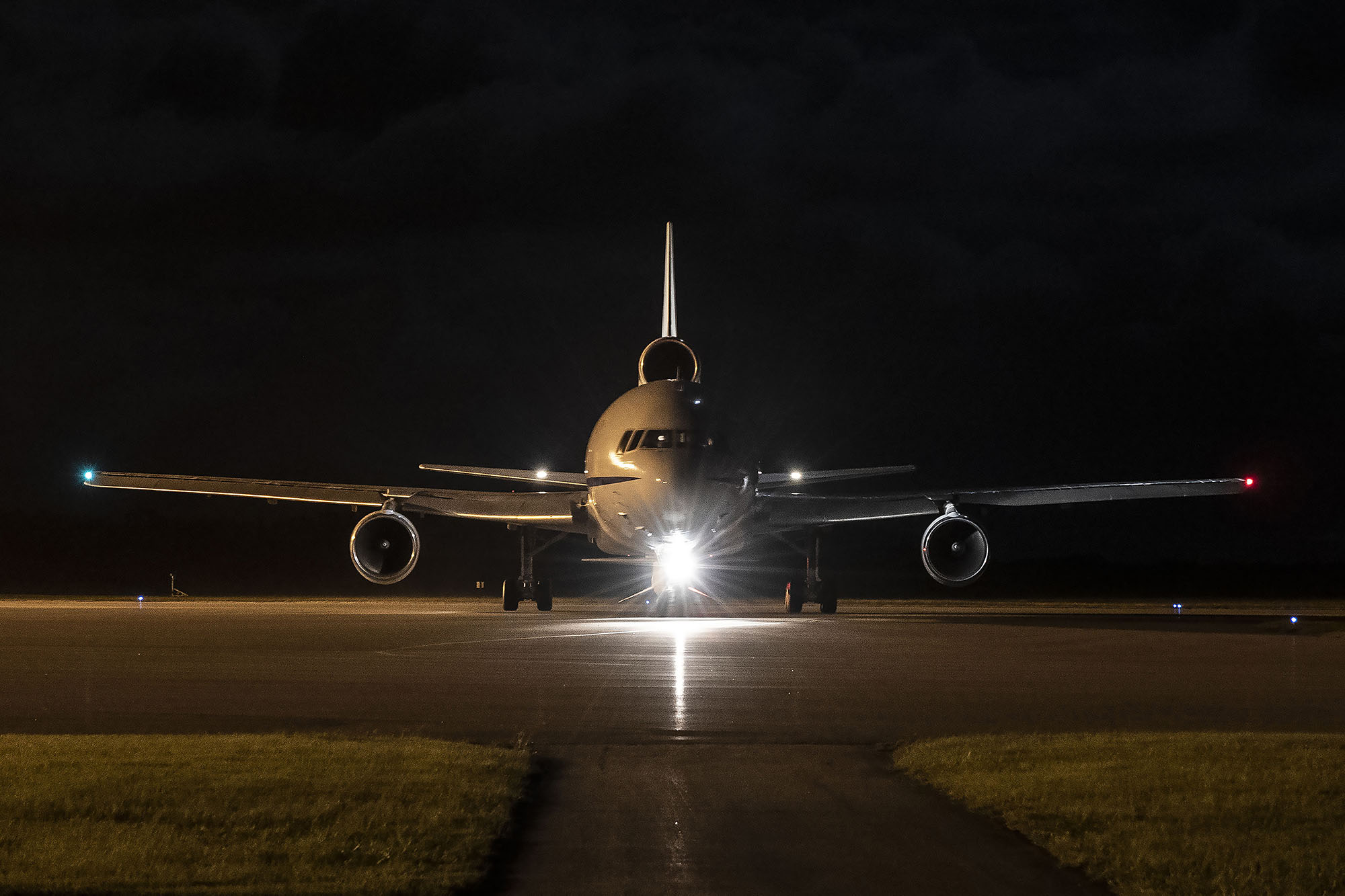 L1011 Taxi Resize Front view of airplane with bright headlight on runway in front of night sky readying for takeoff