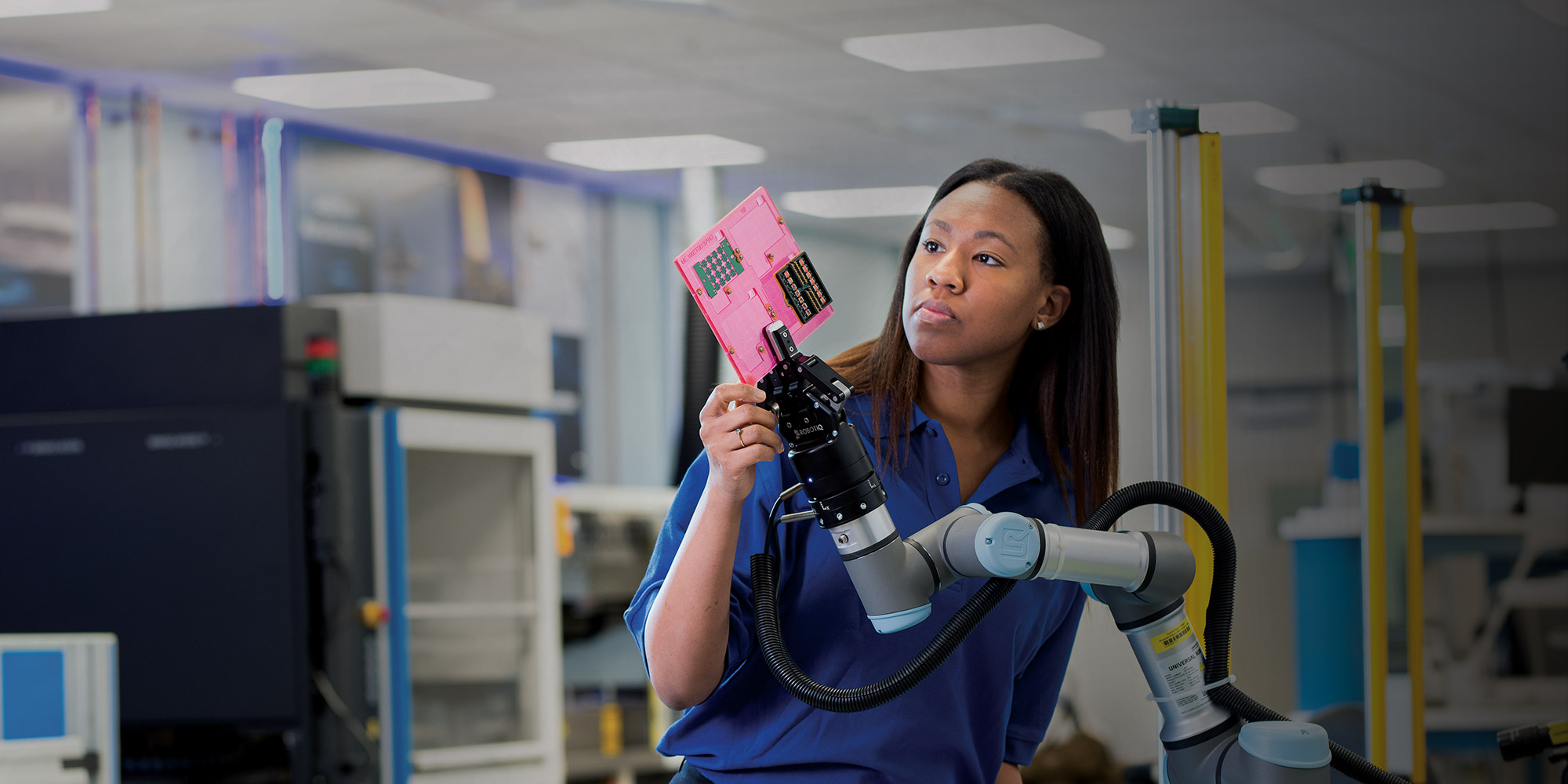 Modern Manufacturing: Deep Learning for Electronics Inspections black woman working with robot arm holding microchip